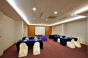 A conference room with multiple tables and chairs, a projector screen, and a carpeted floor. - Hotel Royal Singapore (Singapore)