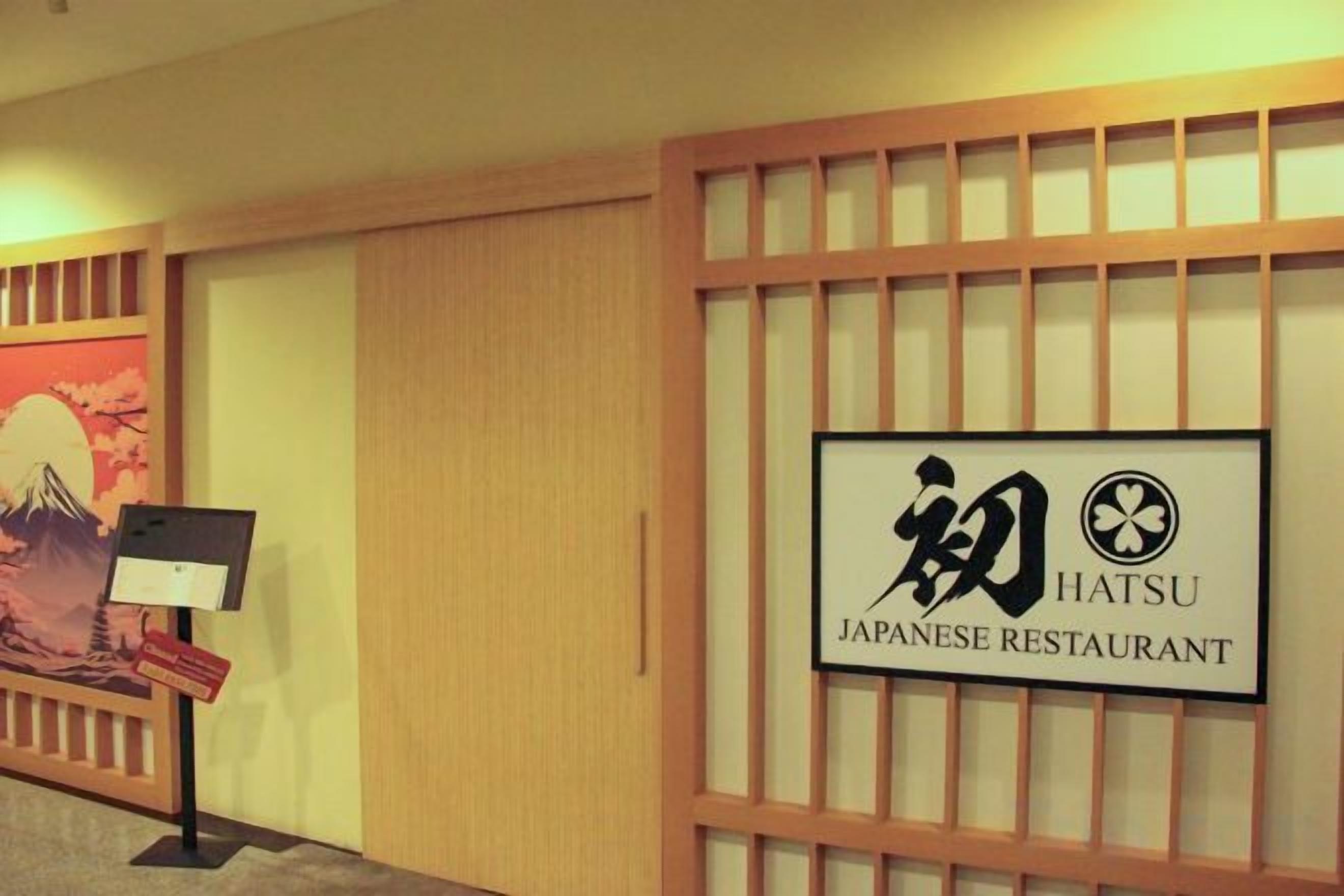 Letrero de restaurante japonés con diseño tradicional y vista a un pasillo con un cuadro y un expositor.