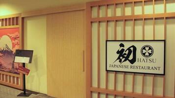 Letrero de restaurante japonés con diseño tradicional y vista a un pasillo con un cuadro y un expositor.