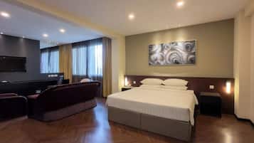 Une chambre d’hôtel avec un grand lit, un canapé, une télévision et un tableau au mur.