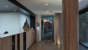 Un espace d’accueil moderne avec un comptoir de réception en bois, une grande colonne à rayures et une lampe suspendue.