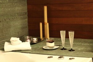 Un cuarto de spa con pared de madera, una toalla, una copa de vino tinto y dos copas de champán sobre una mesa.