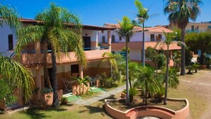 Un edificio residenziale con cortile, palme e una piccola piscina.