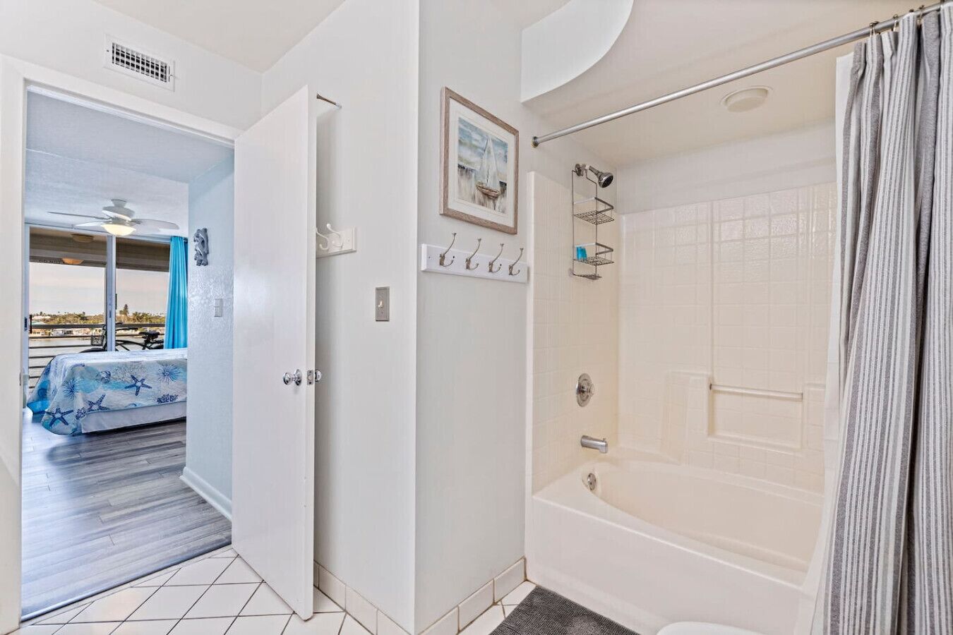A bathroom with a bathtub, shower, and a door leading to a balcony with a view.