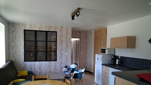 Un espacio habitable compacto con comedor, kitchenette y un amplio ventanal.