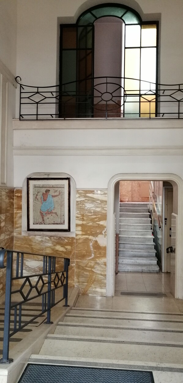 A staircase with a handrail, a framed picture on the wall, and a window with a view of the outside. - Apartment Casa Rosalia (Roma)