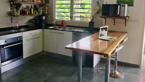 Eine moderne Küche mit Einbauofen, Spüle und einem Holztisch mit einem Laptop.