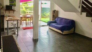 Ein modernes Wohnzimmer mit einer Couch, einem Esstisch und einer Küchenzeile inklusive Mikrowelle.