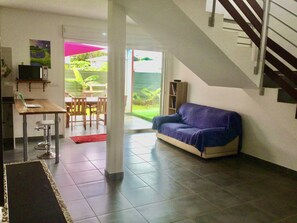 Ein modernes Wohnzimmer mit einer Couch, einem Esstisch und einer Küchenzeile inklusive Mikrowelle.