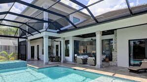 Une maison moderne dotée d ’une piscine, d’un patio couvert et d’un coin repas.