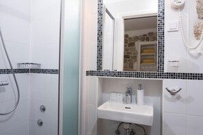 Een badkamer met een douche, een wastafel en een spiegel.