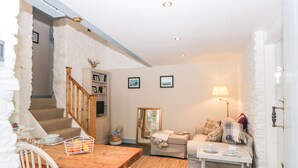 A cozy living room with a wooden staircase, a sofa, a table with a tray, and a lamp. - The Old Dairy (Torpoint)