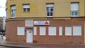 A building with a sign reading "Hostal Las Fronteras." It has a curved facade with multiple windows and a door. - Hostal Las Fronteras (Torrejón de Ardoz)