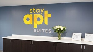 A reception desk with a blue wall, a white counter, and dark cabinets. There is a vase with white flowers on the counter.
