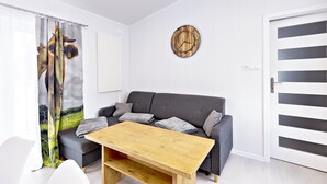 Een moderne woonkamer met een grijze bank, een houten salontafel en een wandklok.