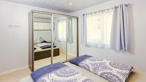 Een slaapkamer met een bed, een kledingkast en een raam met gordijnen.