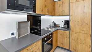 Een moderne keuken met houten kastjes, een ingebouwde magnetron, roestvrijstalen apparatuur en een koffiezetapparaat.