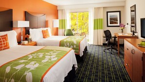 Une chambre d’hôtel avec deux lits, un bureau, une chaise, une télévision et une fenêtre avec des rideaux.