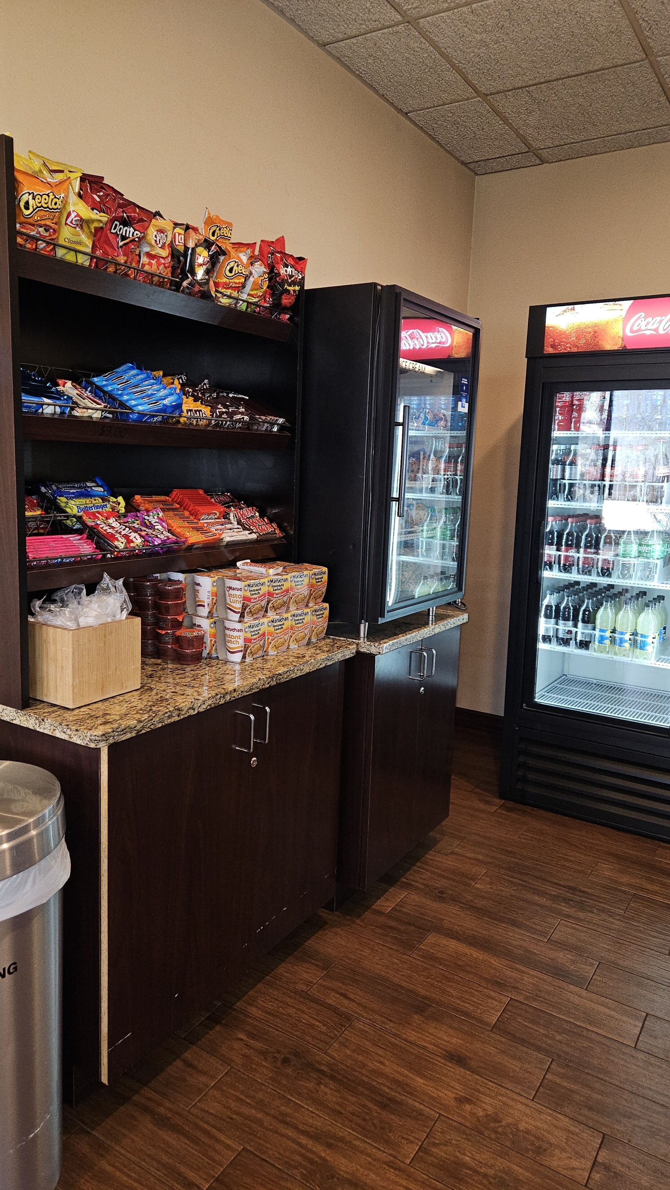 A snack bar with shelves stocked with various snacks and a refrigerator with beverages.