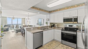 A modern kitchen with white cabinets, stainless steel appliances, and a large island.