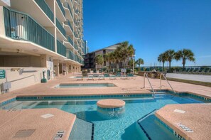 A hotel pool area with multiple swimming pools, lounge chairs, and a building with balconies. - The Ashworth 503 - Ocean Front 3 Bed/3 Bath Condo - Accommodates 10 (North Myrtle Beach)