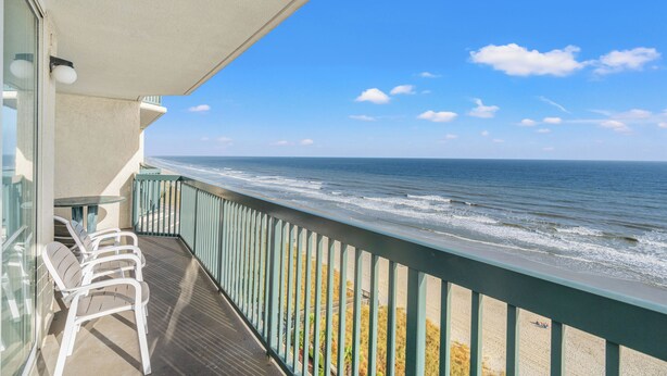 A balcony with a view of the ocean, a table, and white chairs. - Ashworth 1101 - Ocean Front Condo - 4 Bed/3 Bath (North Myrtle Beach)