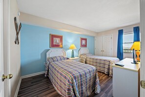 Une chambre avec deux lits, un bureau et une fenêtre avec des rideaux.