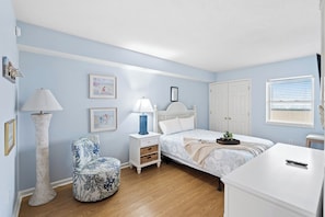 A bedroom with a bed, bedside tables, a lamp, a chair, and a dresser.