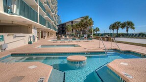 A hotel pool area with multiple swimming pools and lounge chairs.