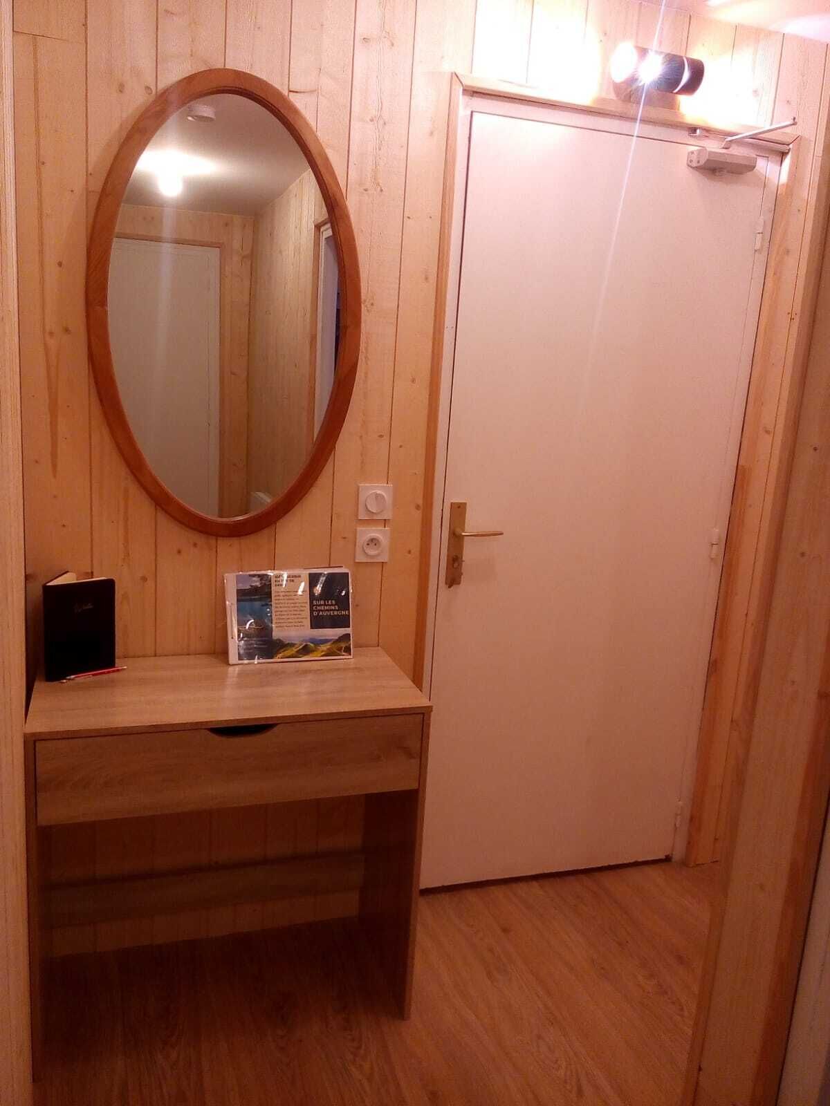 A wooden vanity with a round mirror, a book, and a brochure on the counter.