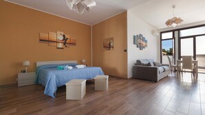 A modern hotel room with a large bed, a sofa, and a dining area. - B&B Joy Home - Camera 3 (Maruggio)