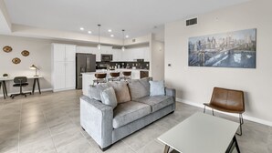 Un salon moderne avec un canapé gris, une table à manger et une cuisine en arrière-plan.