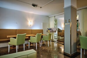 Un restaurante con sillas verdes y una zona con asientos tipo banca.