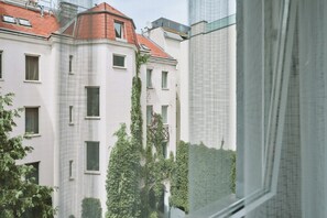 Un edificio de varios pisos con techo de tejas rojas, paredes blancas y numerosas ventanas.