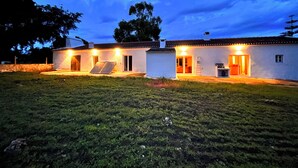 Une maison à deux étages dotée d’un patio, d’une petite dépendance attenante et d’une pelouse bien entretenue.