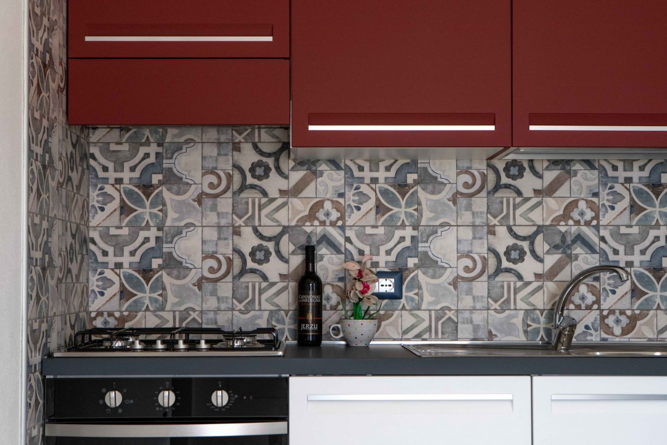 A kitchen with a gas stove, a wine bottle, and a sink.