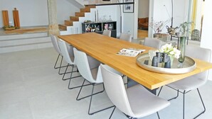 A modern dining area with a wooden table, white chairs, and a central island with a tray. - Villa Bianca, luxury overlooking Canyelles petites beach. Heated pool (Roses)