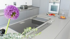 A modern kitchen with a built-in induction cooktop, a toaster, a refrigerator, and a fruit bowl. - Villa Bianca, luxury overlooking Canyelles petites beach. Heated pool (Roses)