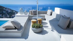 A modern outdoor seating area with a pool, white furniture, and a view of the sea. - Villa Bianca, luxury overlooking Canyelles petites beach. Heated pool (Roses)