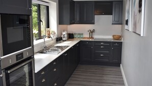 A modern kitchen with dark cabinetry, a built-in oven, and a large window providing natural light.