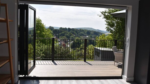 A room with a sliding glass door leading to an outdoor deck with a view of a hilly landscape.