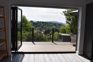 Ein Zimmer mit einer Schiebetür und Zugang zu einer Terrasse mit Blick auf eine hügelige Landschaft.