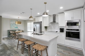 Enjoy cooking in this well-equipped kitchen with a central island, stainless steel appliances, and white cabinetry.