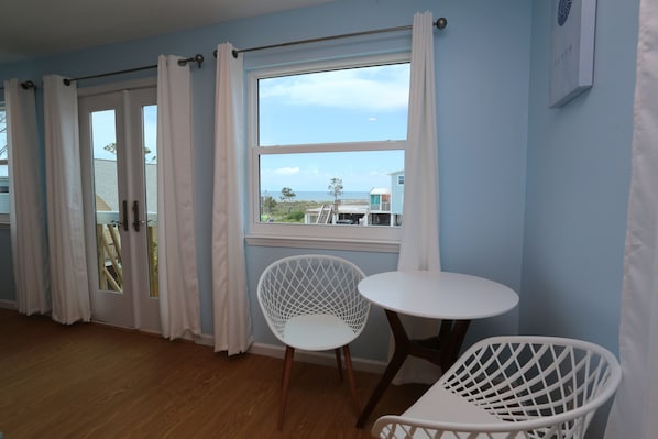 Enjoy a beach view from this room featuring a comfortable chair and a table.
