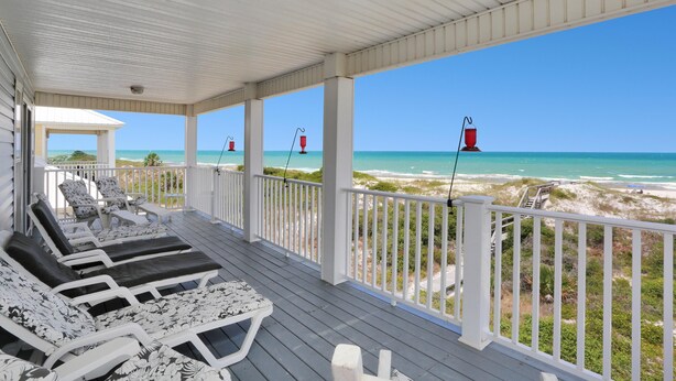 A covered deck with lounge chairs and a view of the beach. - A Tropical Breeze (Port St. Joe)