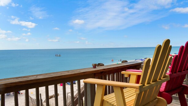 Une terrasse en bois avec des chaises de plage donnant sur une mer calme.