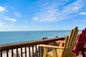 A wooden deck with beach chairs overlooking a calm sea.