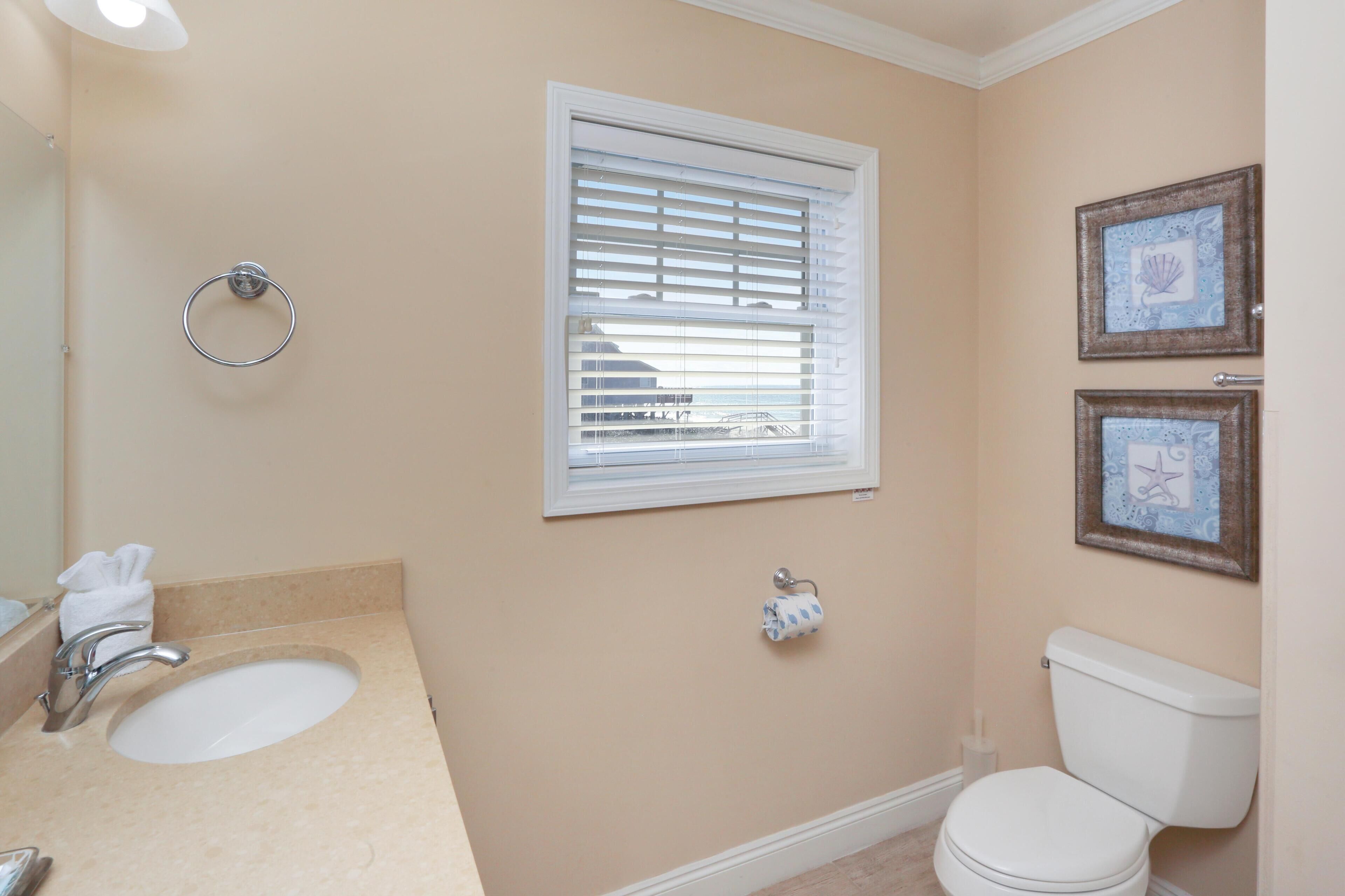 A bathroom with a sink, toilet, and window with blinds.