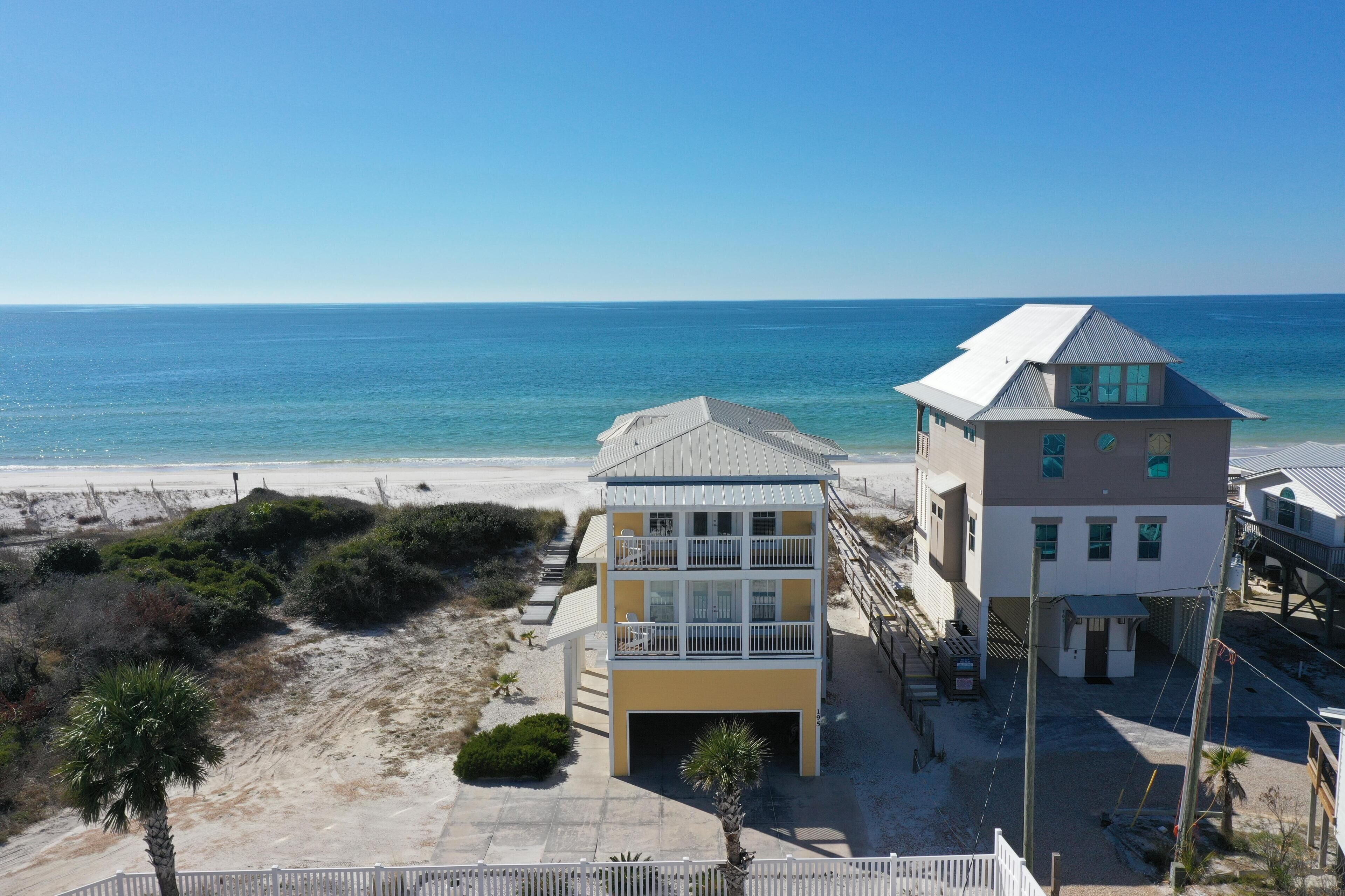 Une propriété située en bord de mer, comprenant un bâtiment à deux étages, un accès direct à la plage et une vue sur l’océan.