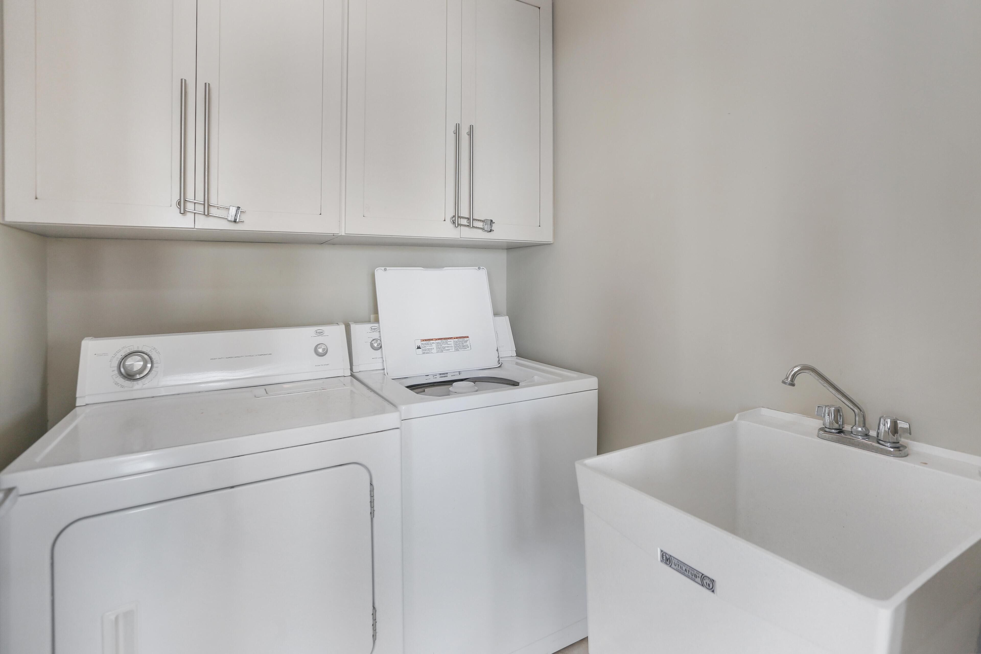 A laundry area with a washing machine, dryer, and a sink.
